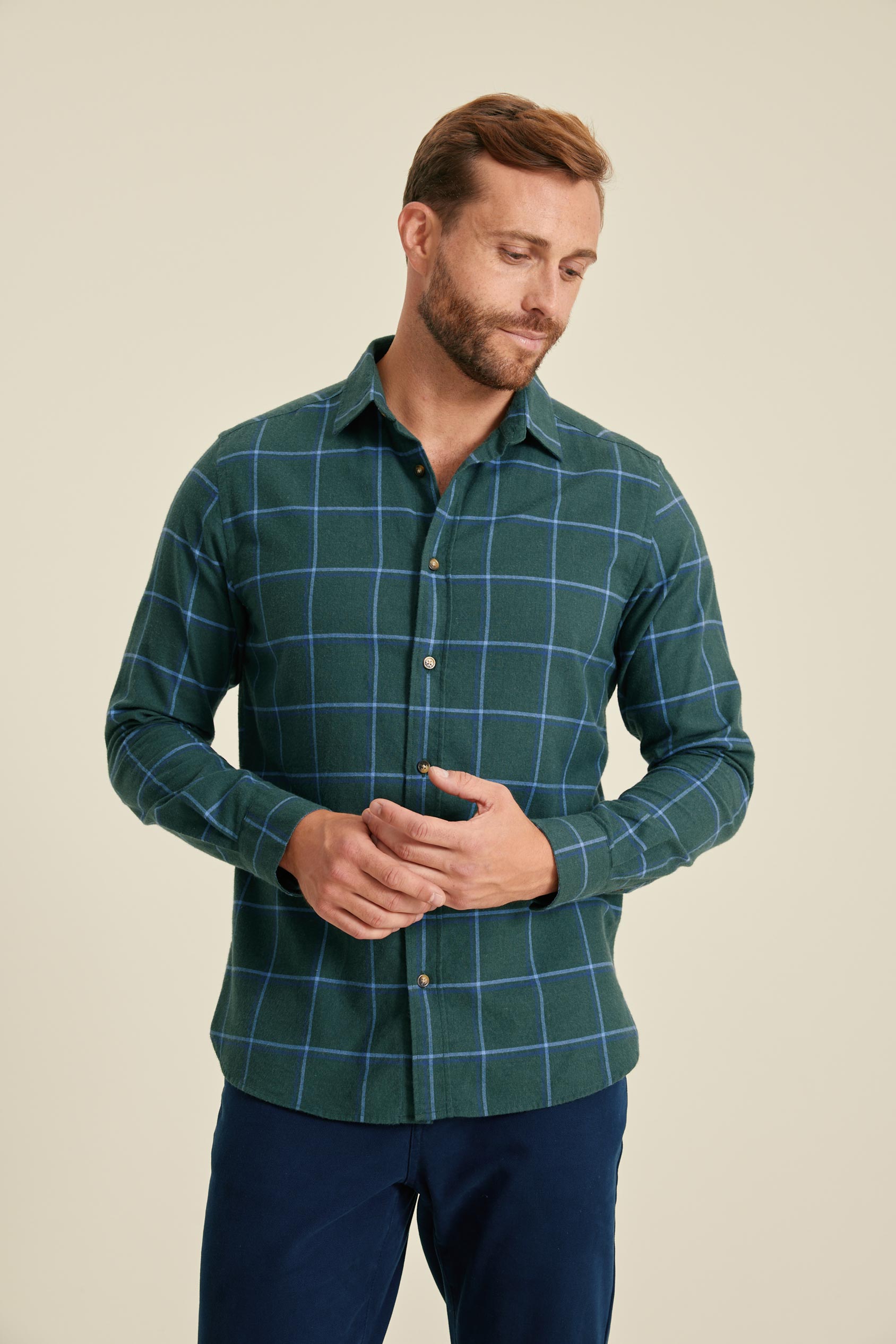 Man wearing a green checkered shirt against a beige background