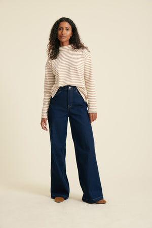 Woman wearing a striped top and blue jeans on a beige background