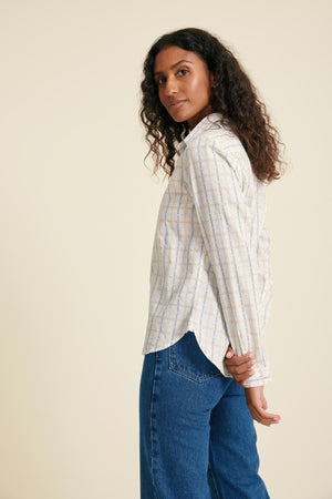 Woman wearing a striped shirt and blue jeans against a beige background