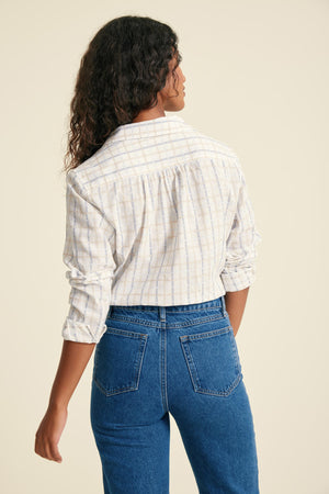 Person wearing a striped shirt and blue jeans on a beige background