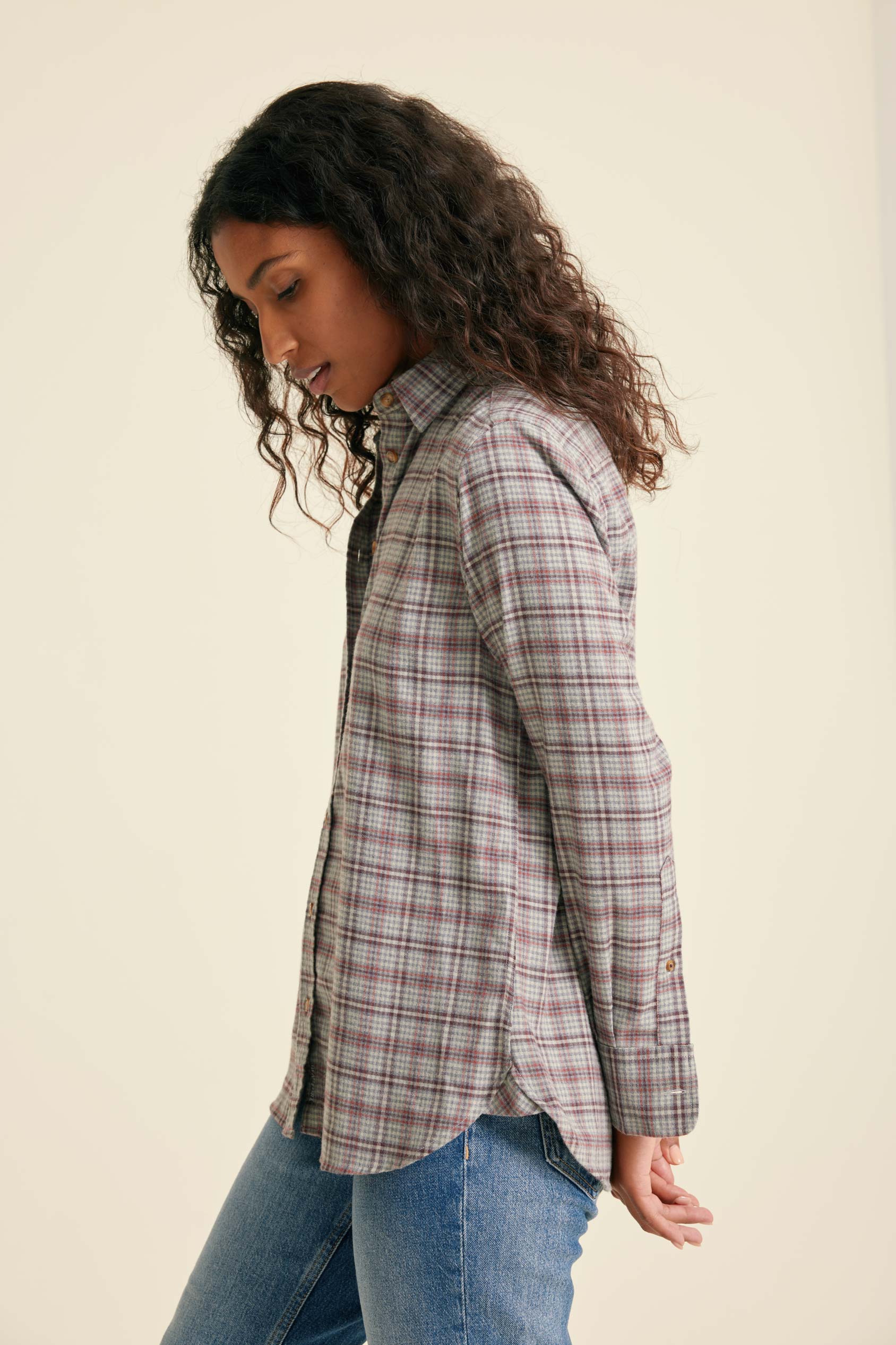 Woman wearing a plaid shirt and jeans against a plain background