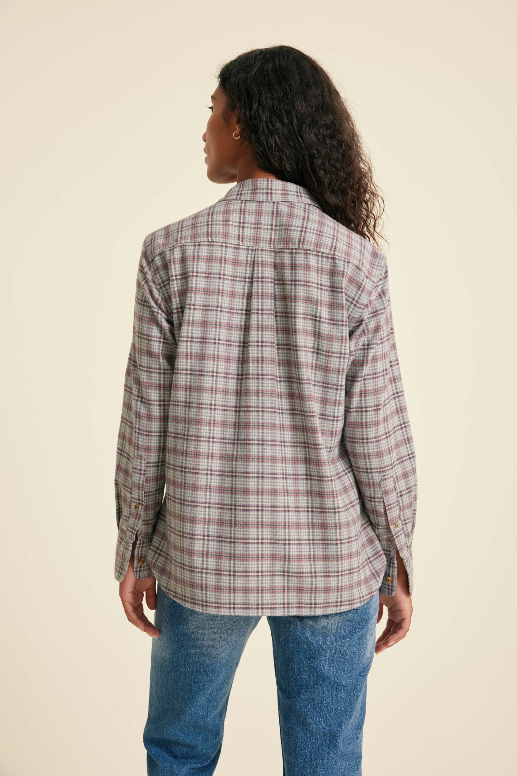 Person wearing a plaid shirt and jeans on a beige background