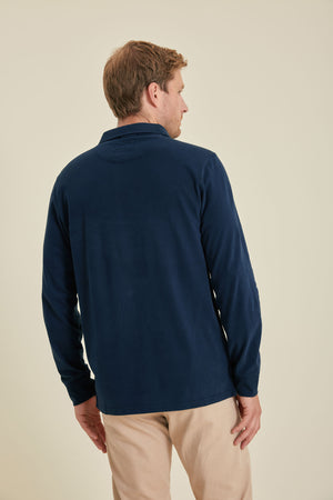 Man wearing a navy long-sleeve shirt and beige pants on a beige background