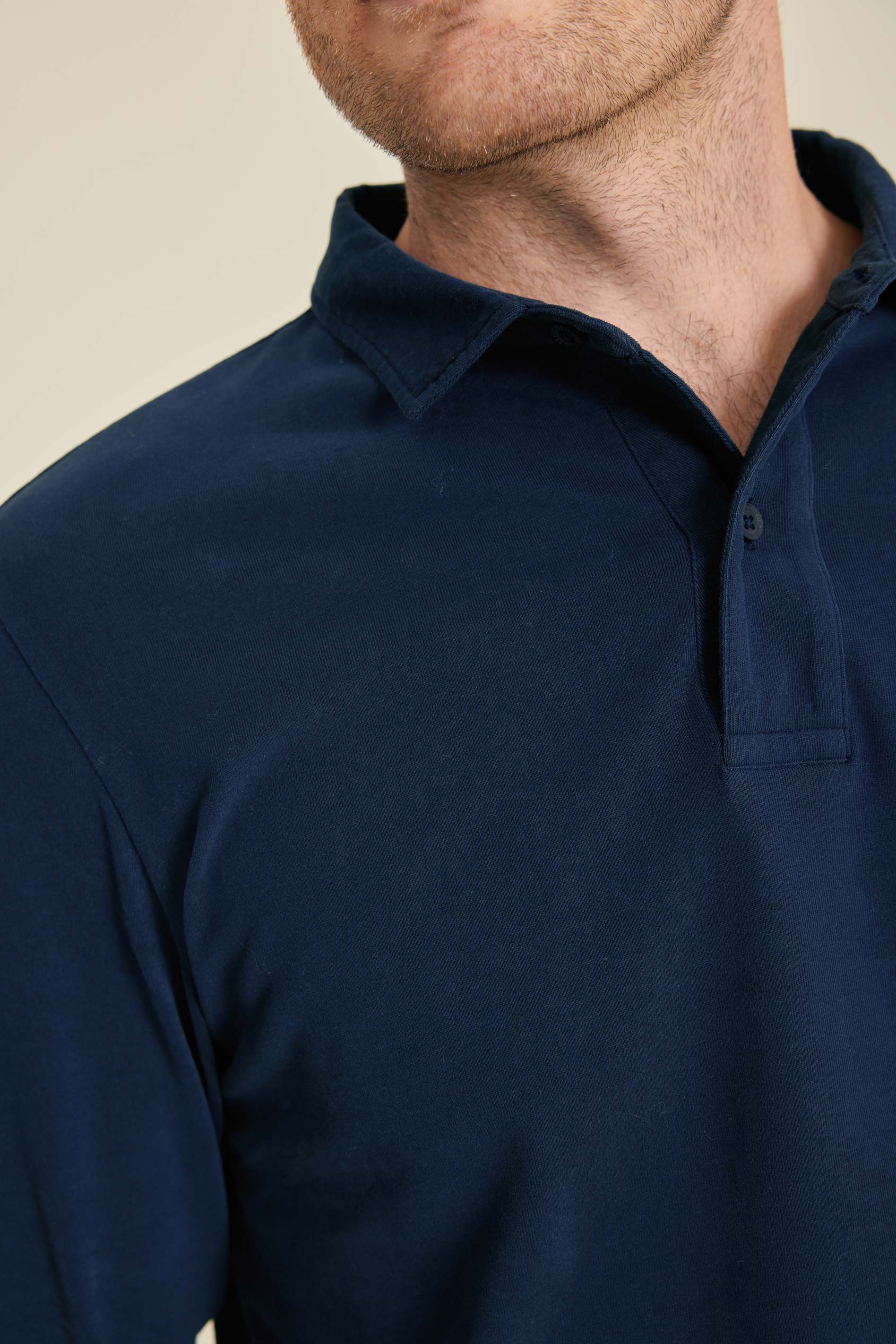 Navy blue polo shirt worn by a person on a beige background
