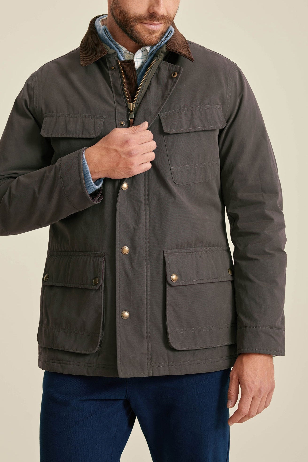 Man wearing a dark brown jacket with a beige background