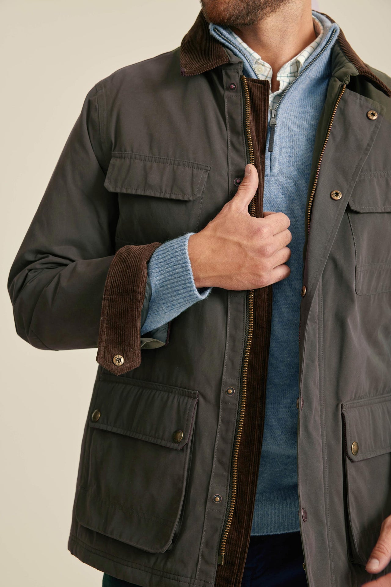 Dark jacket with brown trim worn by a person, against a neutral background