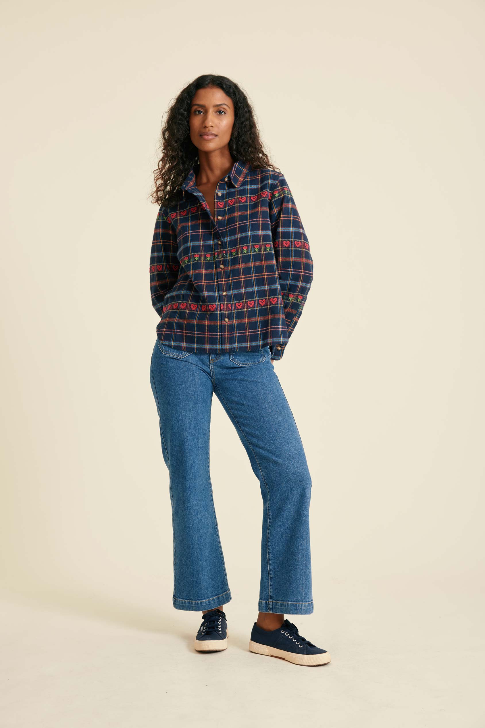 Woman wearing a plaid shirt and blue jeans on a beige background