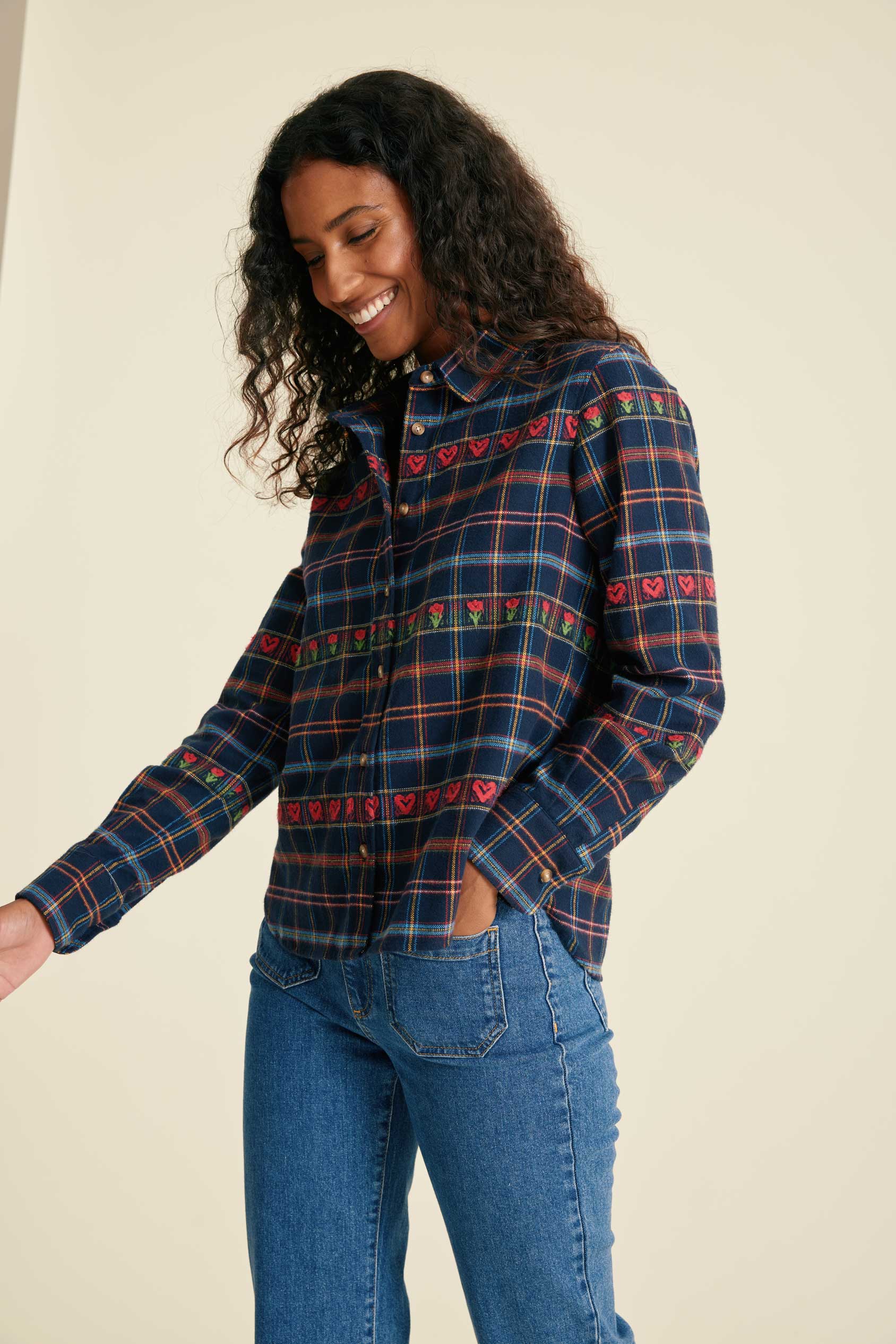 Woman wearing a blue plaid shirt and jeans against a beige background