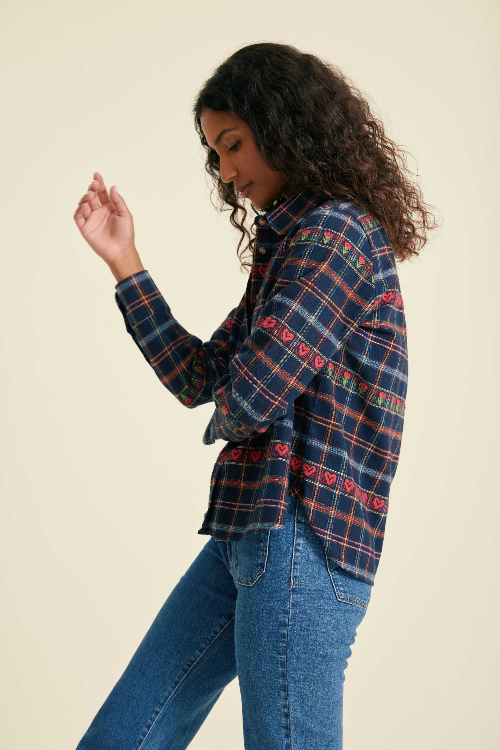 Woman wearing a plaid shirt and jeans on a beige background