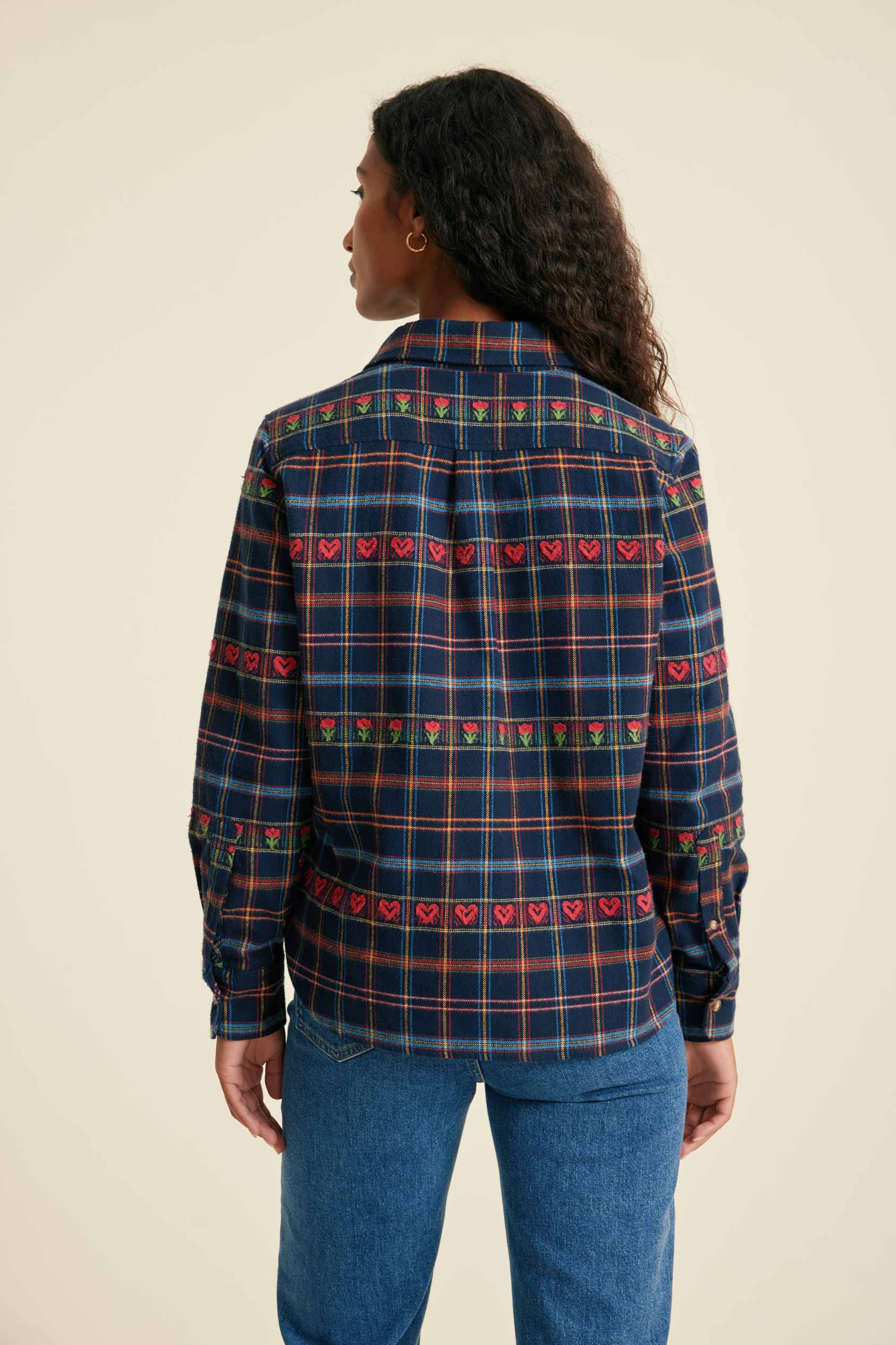 Person wearing a plaid shirt with heart patterns on a beige background