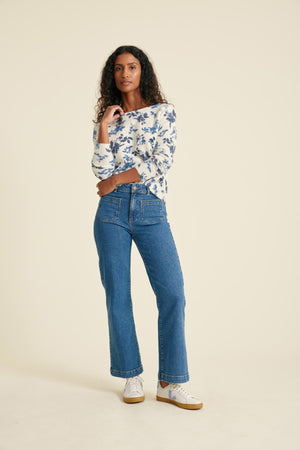 Woman wearing a floral blouse and blue jeans on a beige background