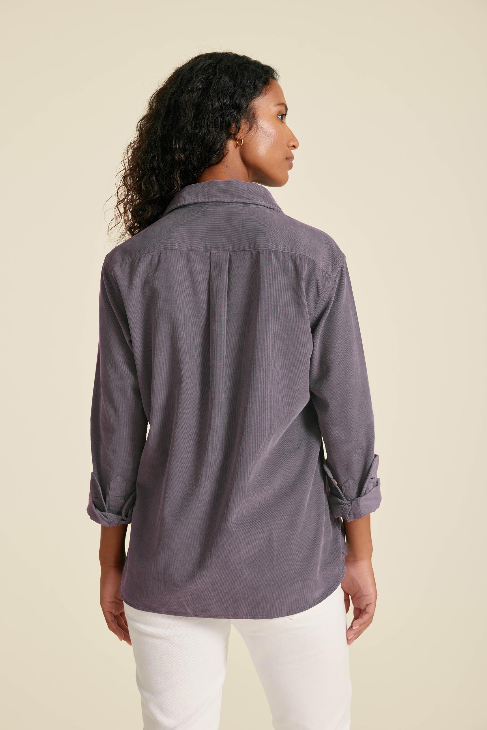 Woman wearing a gray shirt with rolled-up sleeves on a beige background