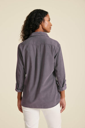 Woman wearing a gray shirt with rolled-up sleeves on a beige background