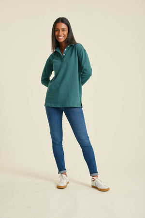 Woman wearing a pine sweatshirt and blue jeans on a beige background