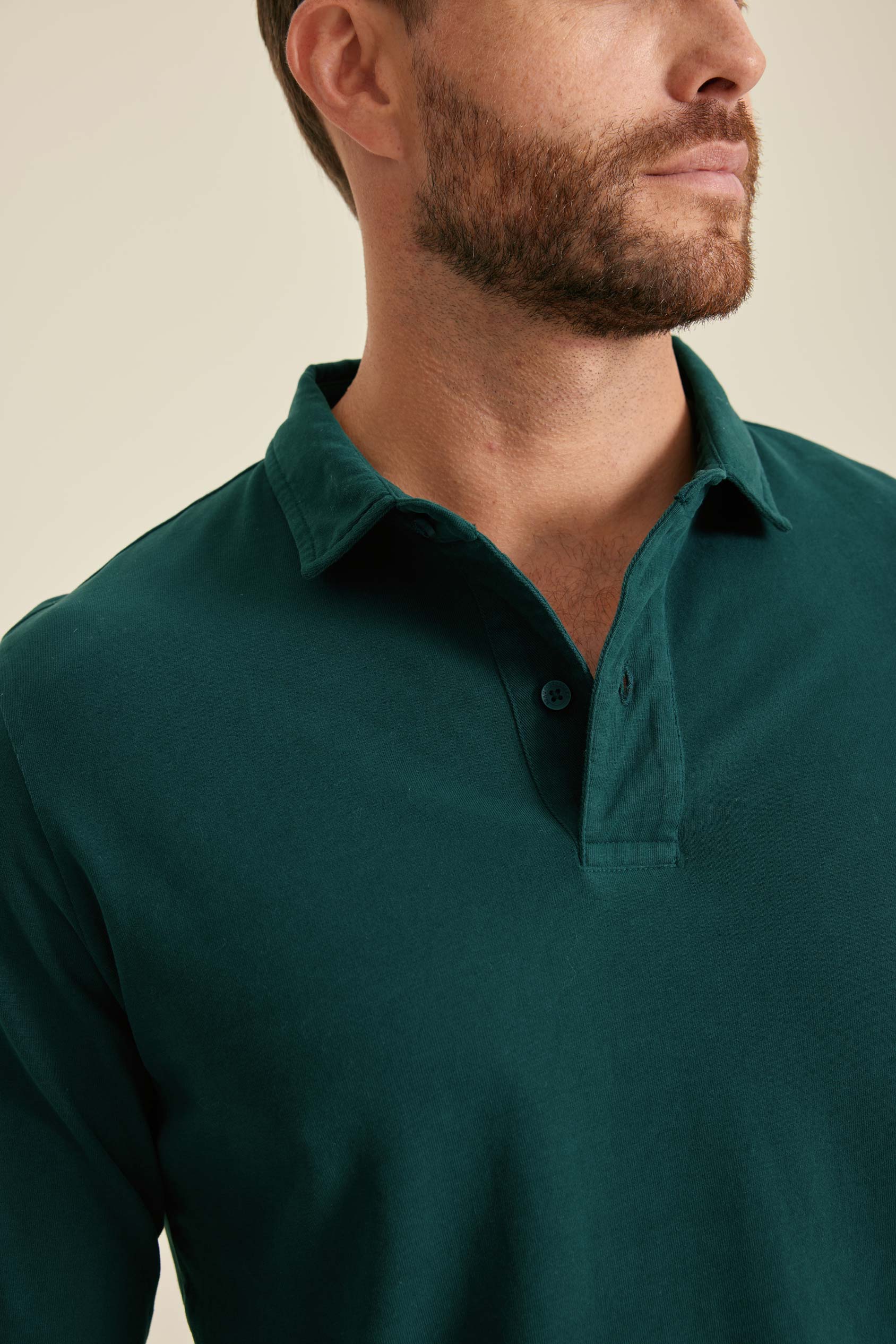 Man wearing a green polo shirt against a beige background