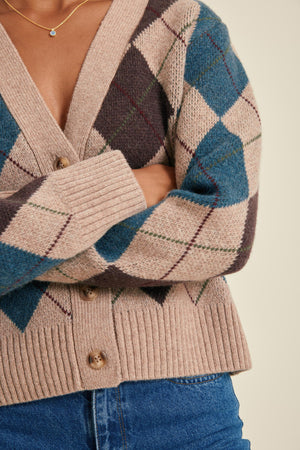 Close-up of a person wearing a patterned cardigan with blue and beige colors.