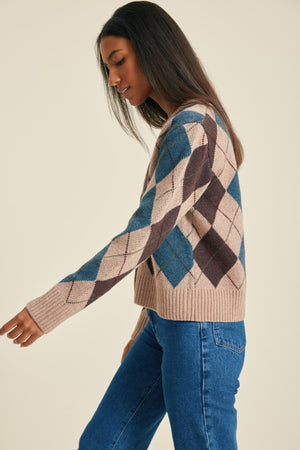 Woman wearing a patterned sweater and blue jeans on a beige background