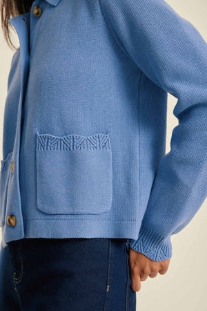 Blue knitted jacket with a textured pocket on a neutral background