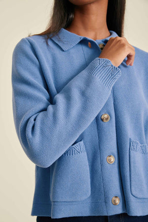Blue knitted cardigan with button details on a neutral background
