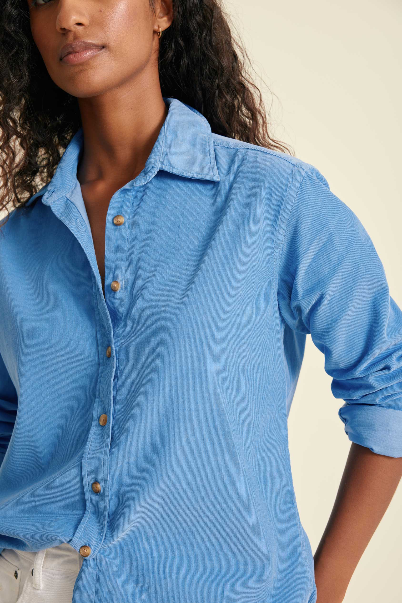 Woman wearing a blue button-up shirt against a beige background