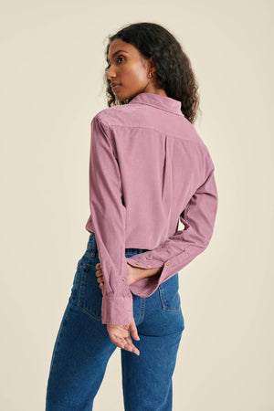 Woman wearing a pink shirt and blue jeans on a beige background