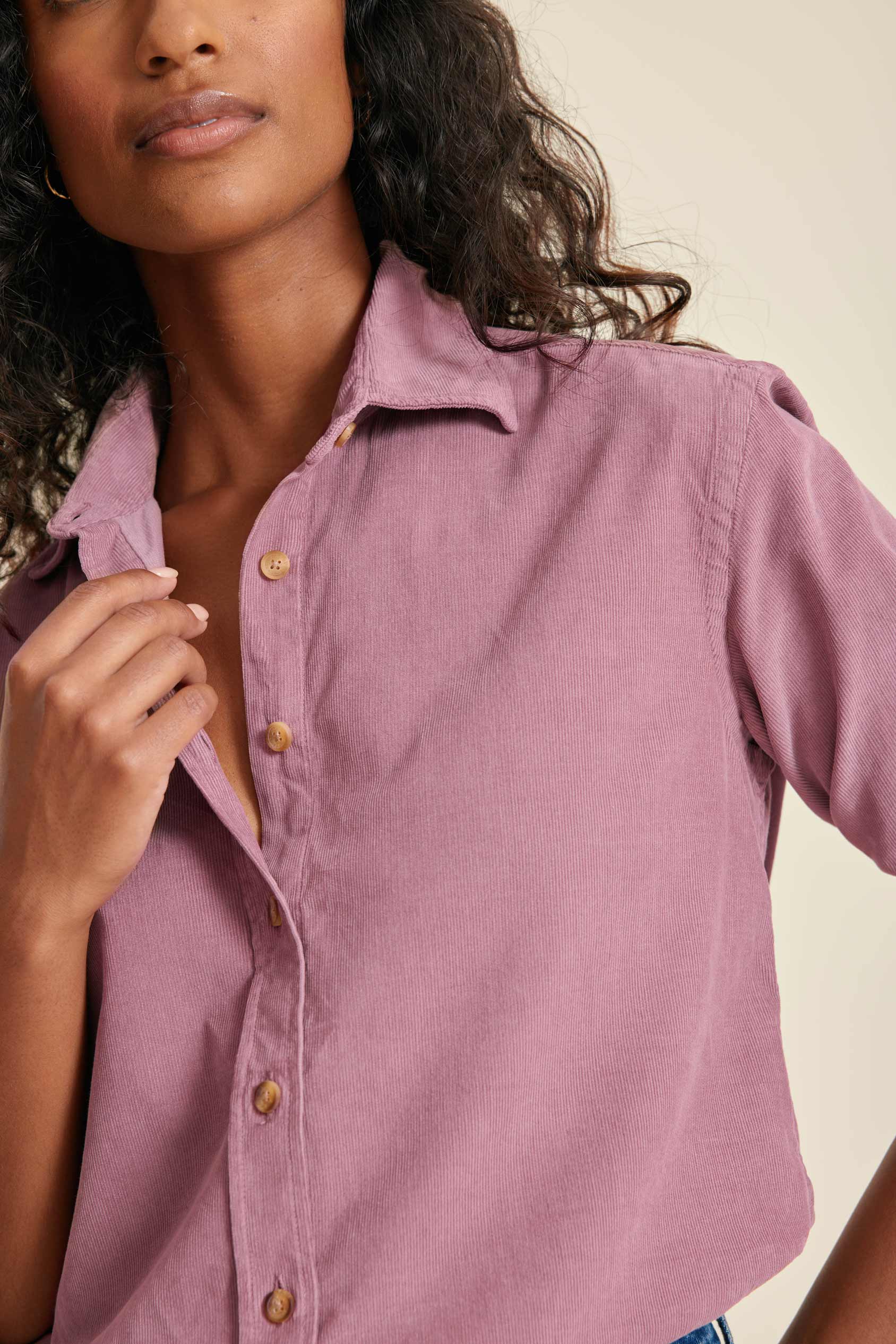 Woman wearing a pink button-up shirt against a neutral background