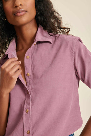 Woman wearing a pink button-up shirt against a neutral background