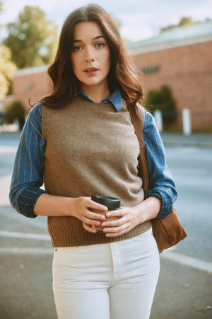 Woman holding a coffee cup and a bag, standing outdoors.