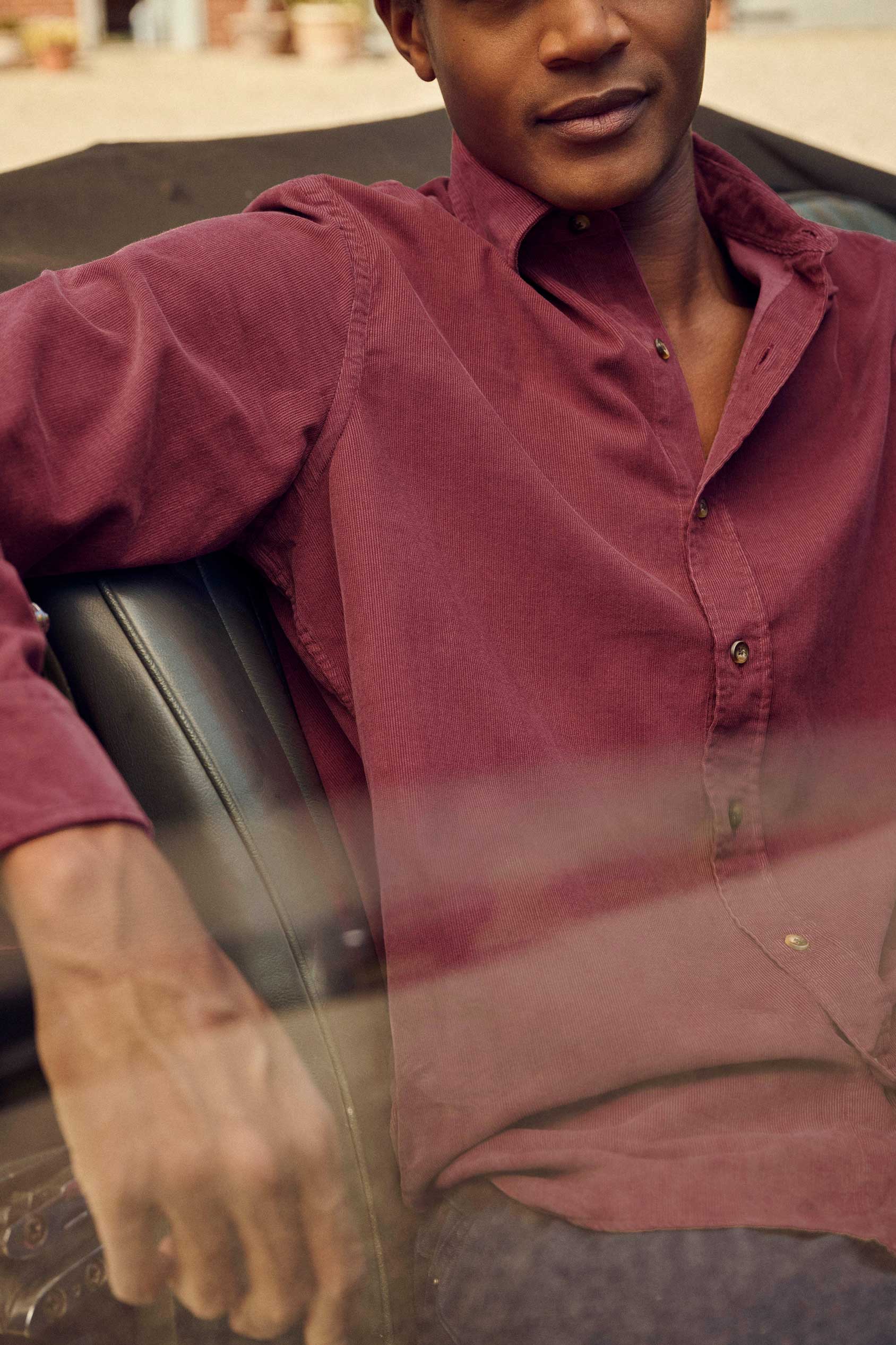 Man wearing a maroon shirt sitting in a car.