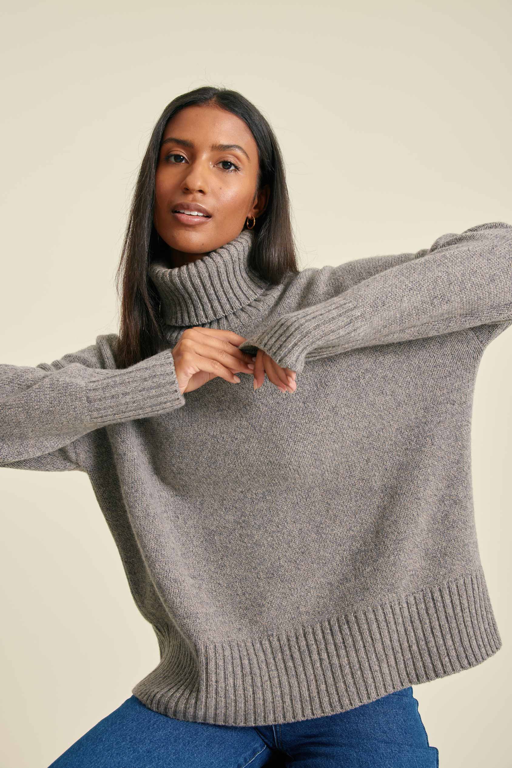Woman wearing a gray sweater with a plain background