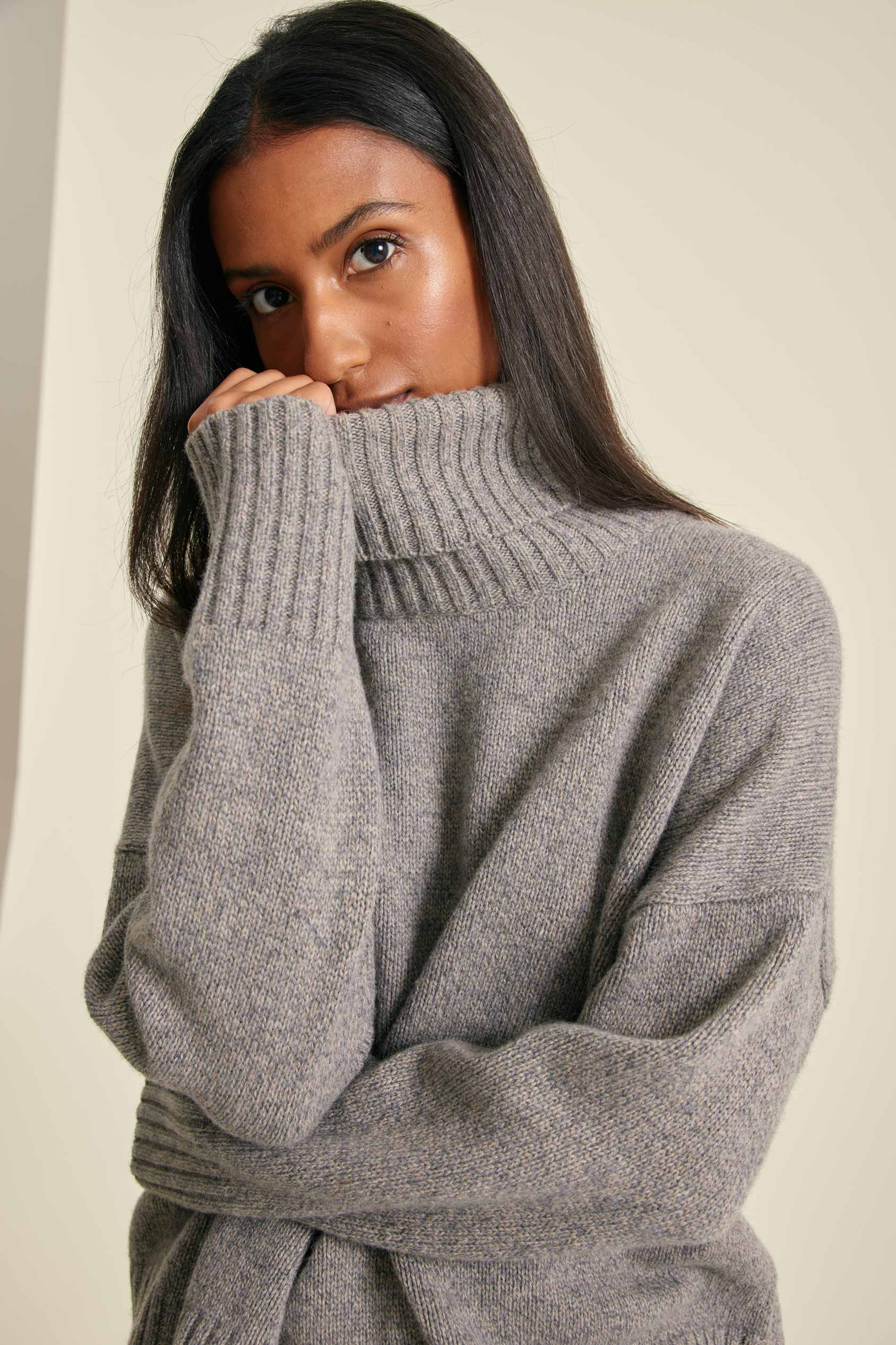 Woman wearing a gray sweater against a plain background