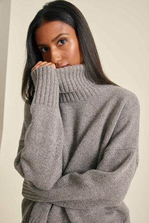 Woman wearing a gray sweater against a plain background