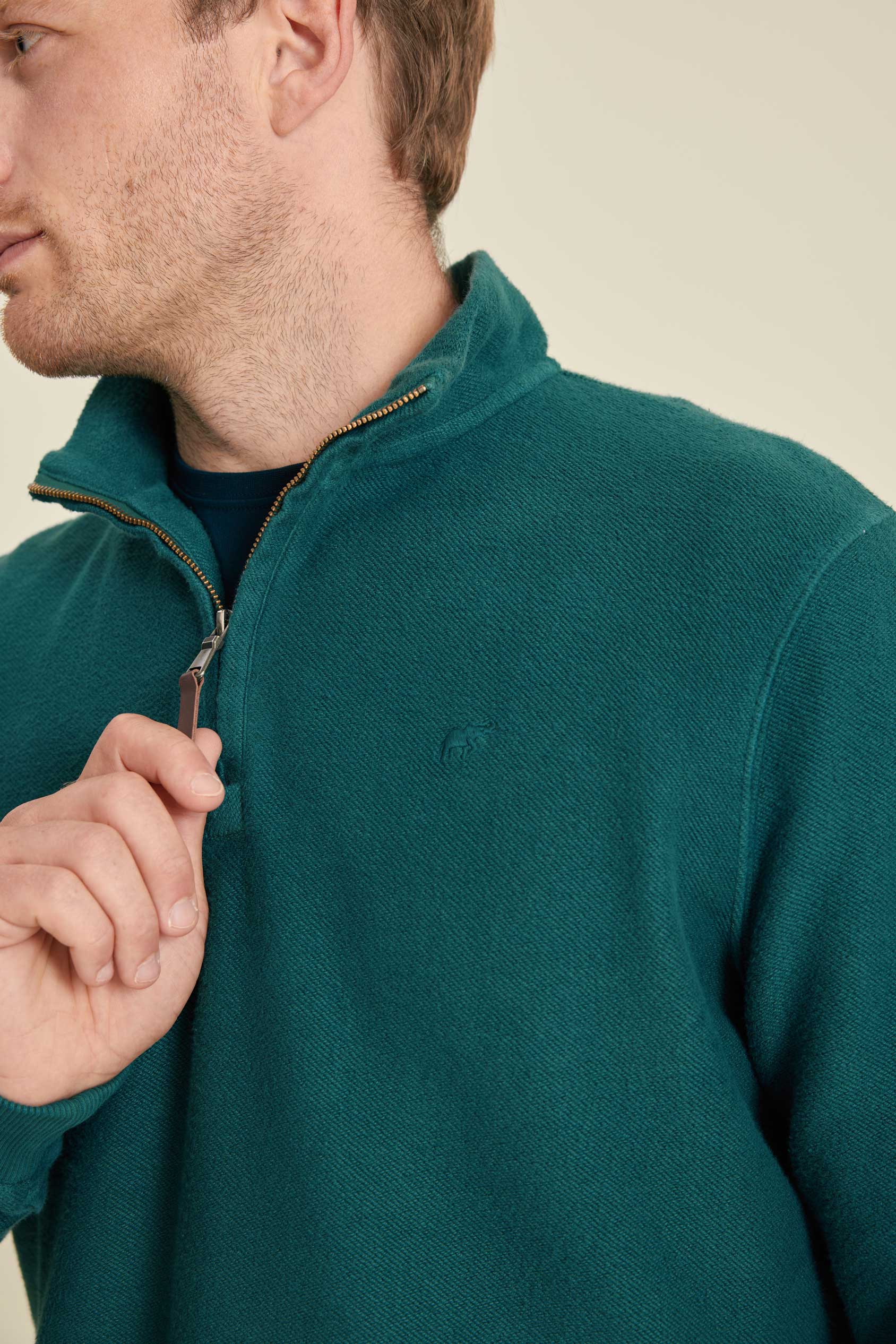 Man wearing a teal fleece jacket with a close-up of the zipper.