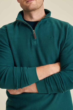 Man wearing a teal pullover with a zipper on a beige background
