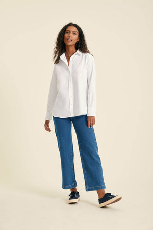 Woman wearing a white shirt and blue jeans on a beige background