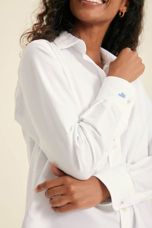 Person wearing a white shirt with a visible brand logo on a plain background