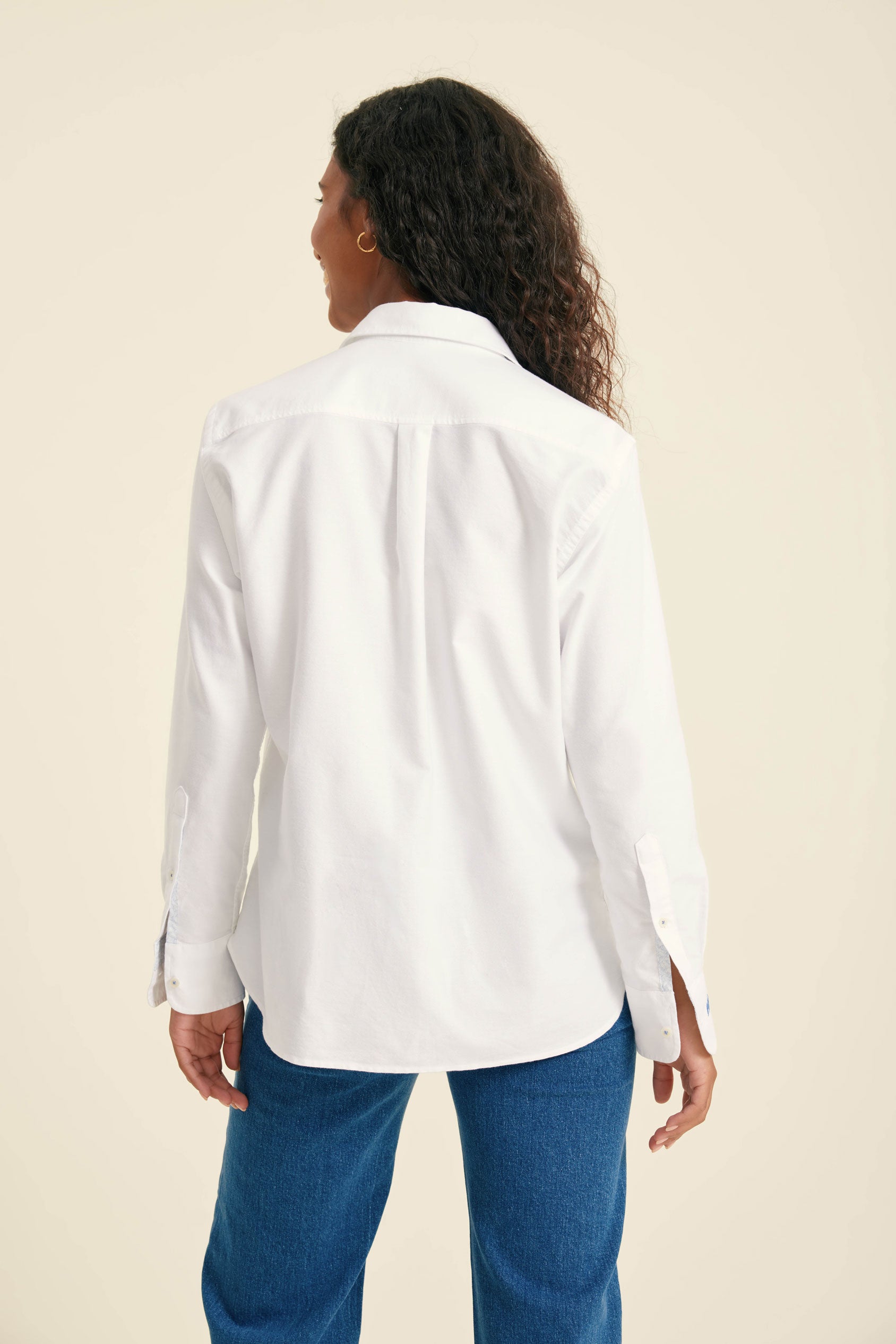 Person wearing a white shirt and blue pants on a beige background