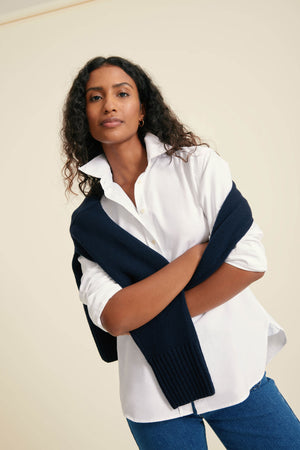 Woman wearing a navy blue scarf over a white shirt with a beige background