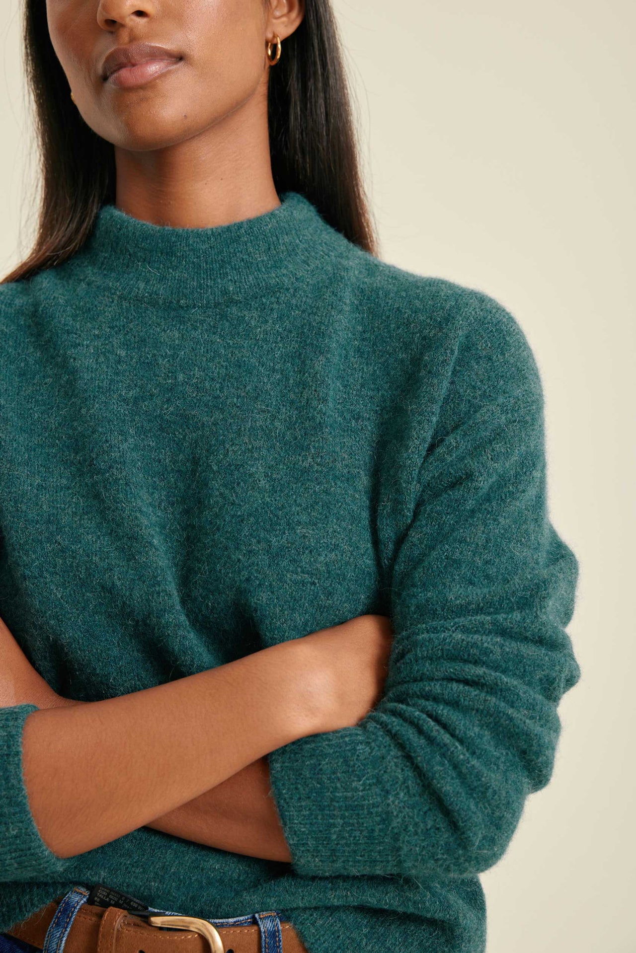 Woman wearing a teal sweater against a neutral background