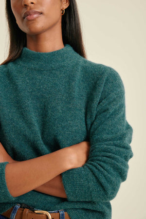 Woman wearing a teal sweater against a neutral background