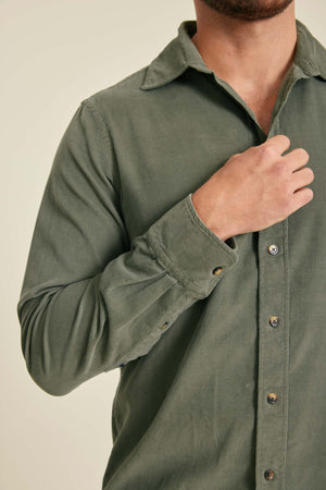 Green shirt worn by a person on a beige background