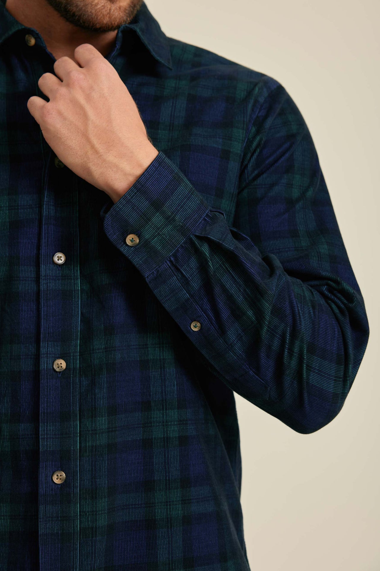 Man wearing a dark blue plaid shirt with a beige background