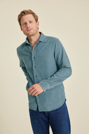 Man wearing a blue shirt and blue pants against a beige background